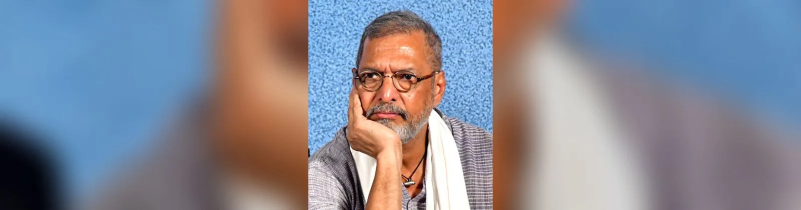 गालावर हात टेकवून विचारमग्न बसलेले ज्येष्ठ अभिनेते नाना पाटेकर; चष्मा, करड्या रंगाचा कुर्ता आणि खांद्यावर पांढरं उपरणं (२०२५ मधील छायाचित्र)